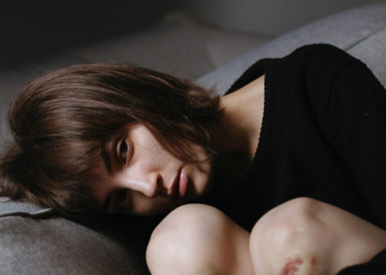 A thoughtful woman posing indoors, showcasing a serene and introspective mood on a sofa.
