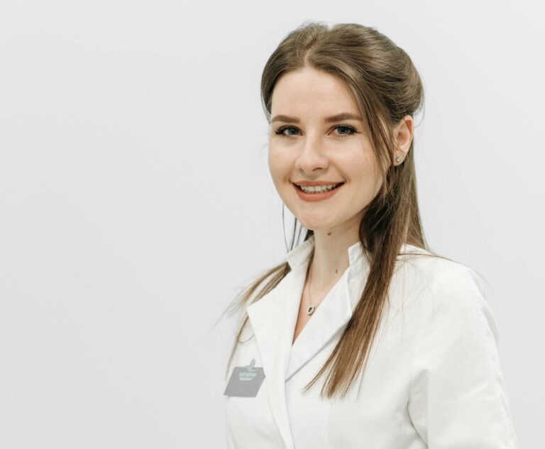 Happy nurse in white uniform holding a medical instrument against a white background.