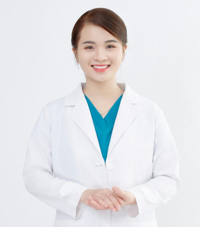 Portrait of a young Asian female doctor smiling confidently in a studio setting.