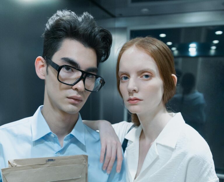 Professional colleagues standing in an elevator with documents, expressing serious demeanor.