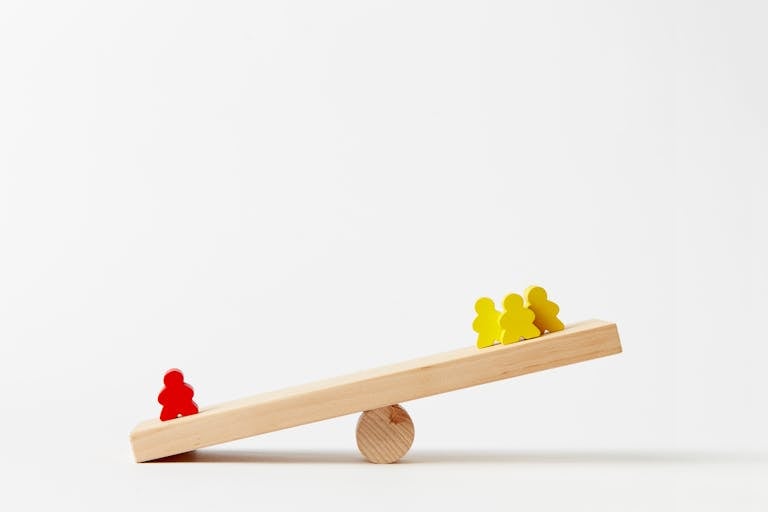 Wooden seesaw toy with colorful figures illustrating balance and play in a minimalist style.